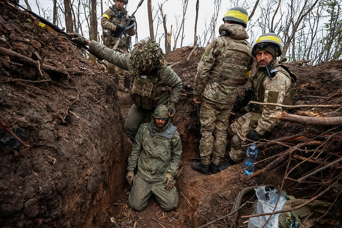 Ukrainian soldiers stay next to a captured Russian army serviceman, according to them, on positions recently gained in an offensive, as Russia's attack on Ukraine continues, near the front line city of Bakhmut, in Donetsk region, Ukraine May 11, 2023. Radio Free Europe/Radio Liberty/Serhii Nuzhnenko via REUTERS
