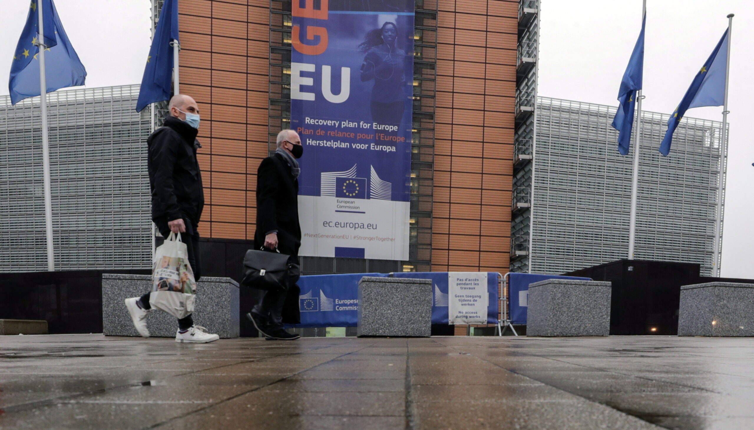 epa08968608 Two persons walk in front of the European Commission headquarters in Brussels, Belgium, 27 January 2021, ahead of a press conference by European Commissioner in charge of Health Stella Kyriakides about deliveries and export transparency scheme for coronavirus disease (COVID-19) vaccines.  EPA/OLIVIER HOSLET